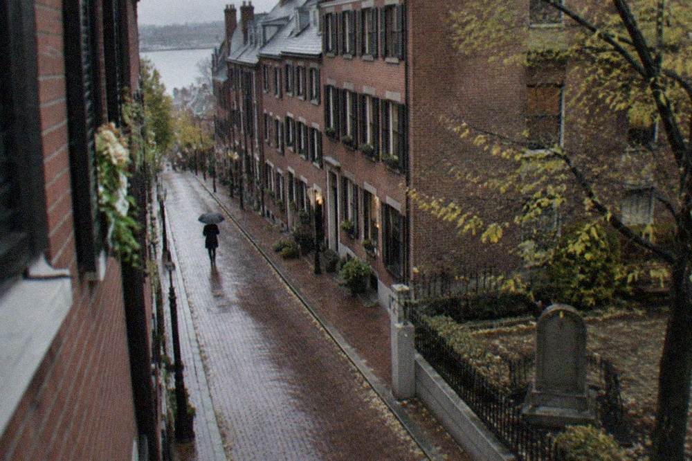Row of brick row houses on a narrow North End street with Italian deli signs