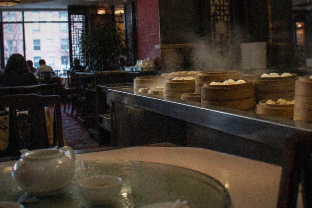 Steam rising from bamboo baskets of dumplings arranged along a restaurant counter