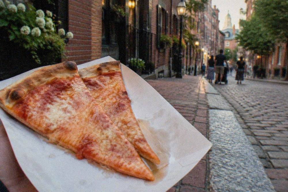 Two slices of cheese pizza on a paper tray held over a North End street