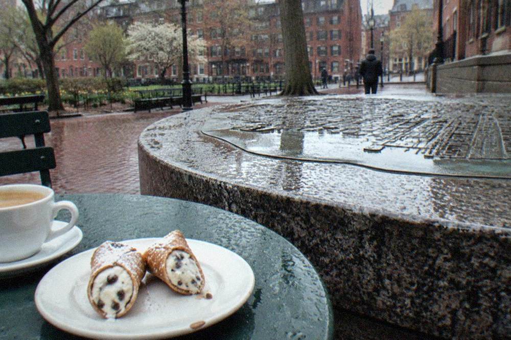 A cannoli cut in half on a small plate beside a cup of coffee