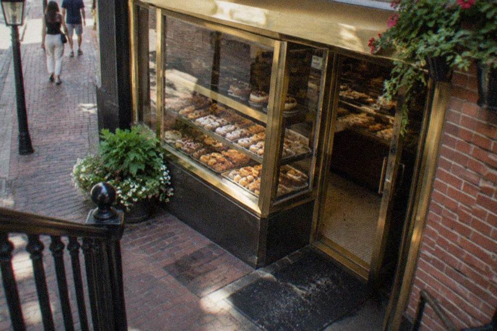 Italian bakery and cafe storefronts along a narrow North End street