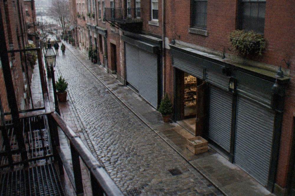 A cobblestone street in the North End lined with Italian shops and red brick buildings