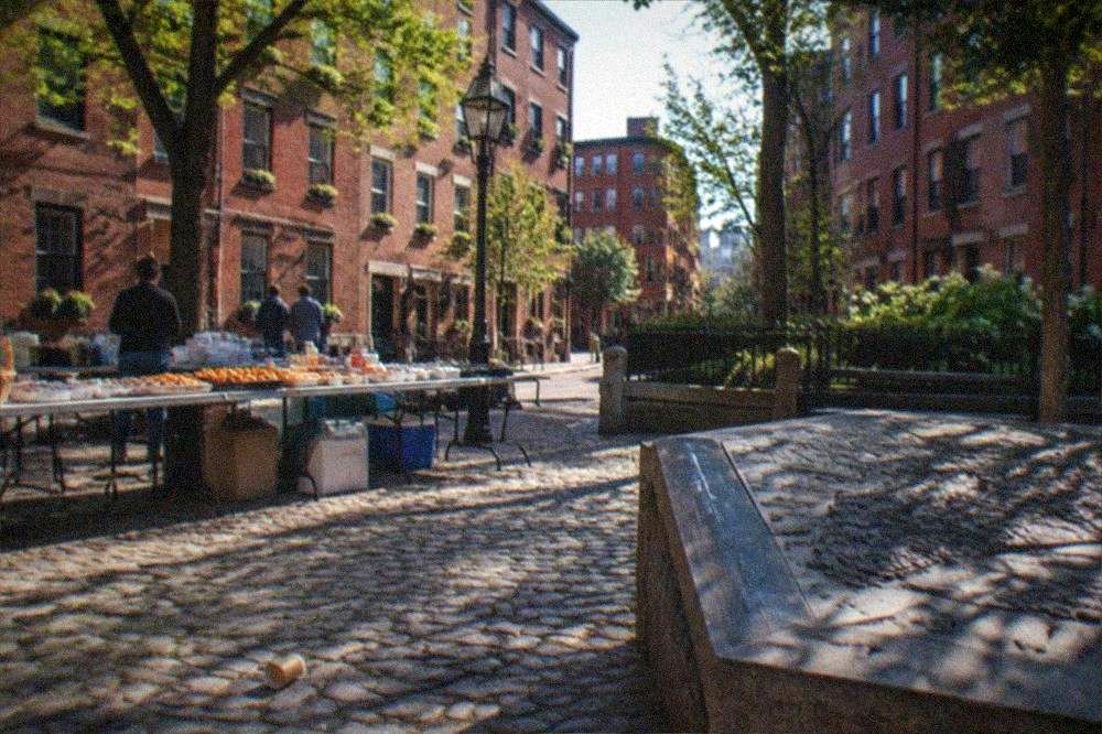 Sunny street corner in a Boston neighborhood with tables of food set out for a walking tour