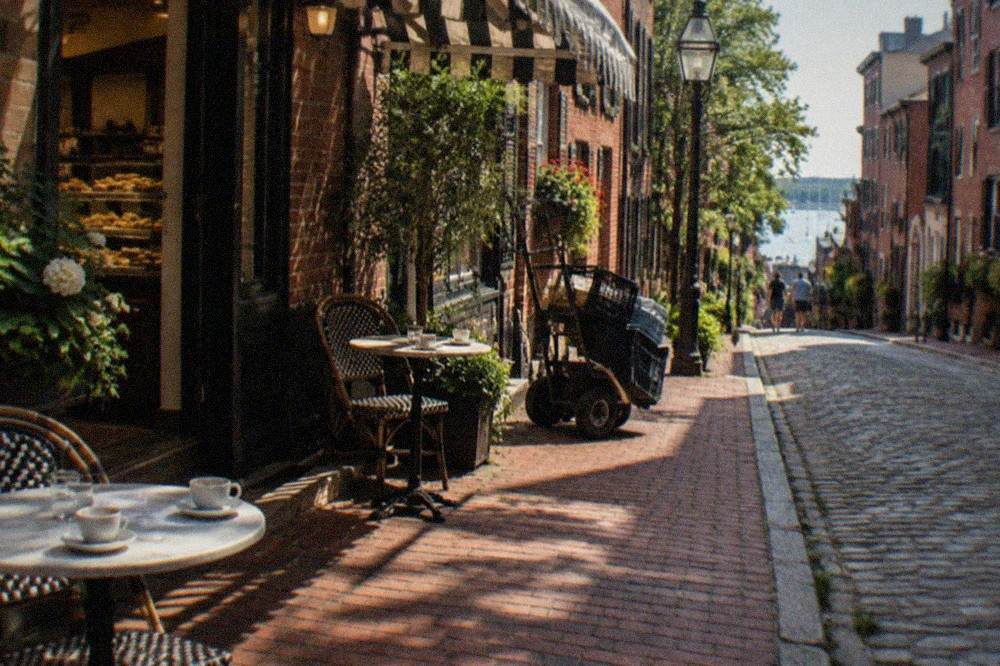 Hanover Street storefronts with Italian bakery signage and outdoor cafe tables