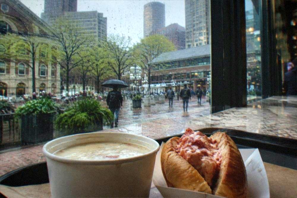 Market food stalls with trays of clam chowder and lobster rolls served across a counter
