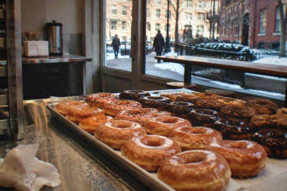 A tray of fresh donuts arranged behind a bakery counter