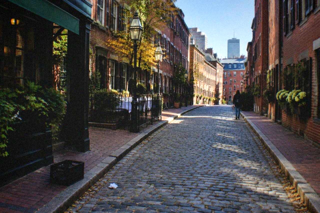 A narrow Boston street lined with old brick row houses and small restaurant storefronts