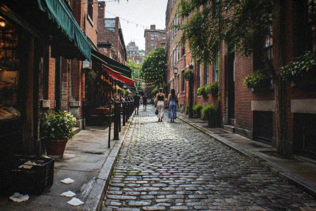 A narrow North End street lined with Italian bakeries and cafés on a busy afternoon