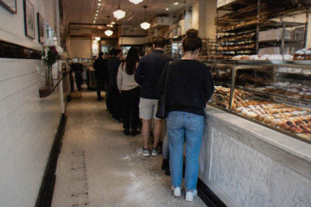 Guided walking group sampling pastries at a bakery counter on a Boston street