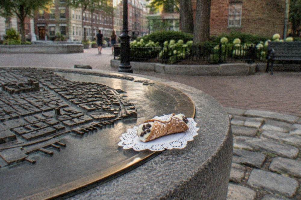 A cannoli filled with ricotta cream and dusted with powdered sugar resting on a paper doily