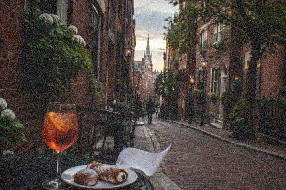 A cocktail glass and a plate of Italian pastries on a marble cafe table