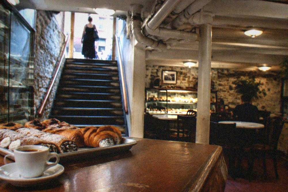 A tray of Italian pastries and a cup of espresso on a wooden bakery counter