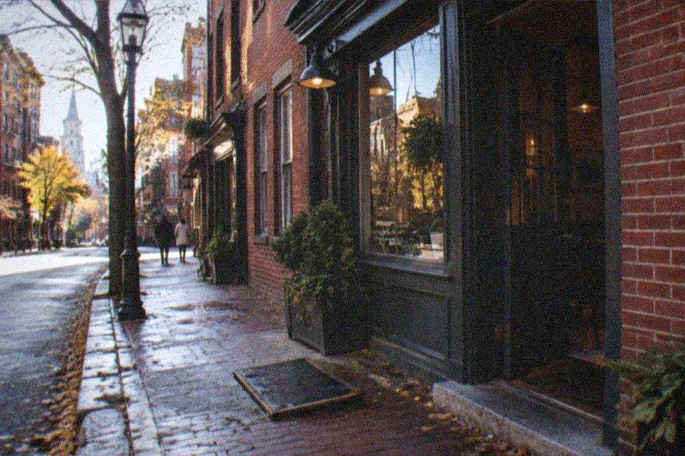 A quiet Hanover Street sidewalk in the North End with storefronts in morning light