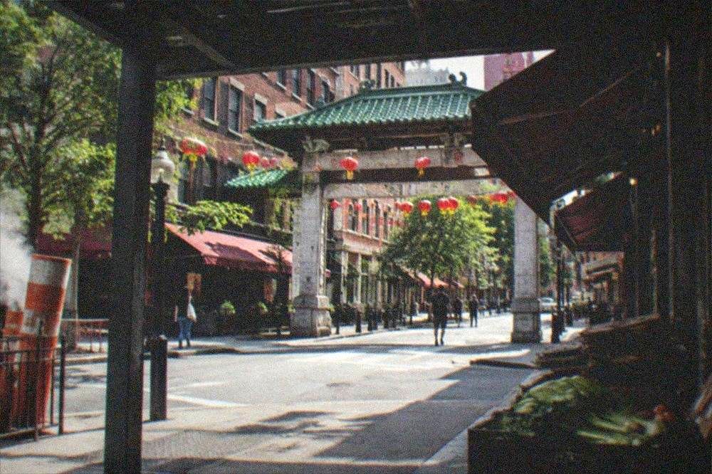 Busy Chinatown gate and street with restaurant awnings and hanging lanterns