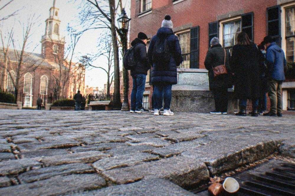 Guided walking group gathered on a cobblestone square beside a historic brick building