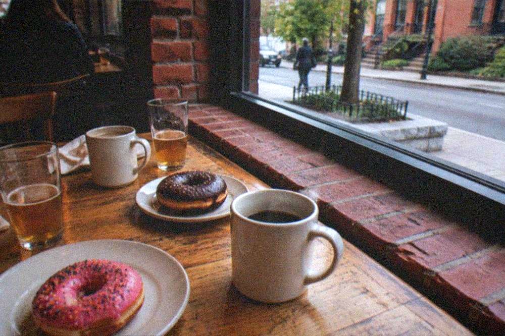 Table spread with fresh donuts, cider glasses and coffee cups in a downtown bakery