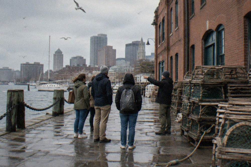 A guide leading a small group past seafood stalls on a Boston waterfront street