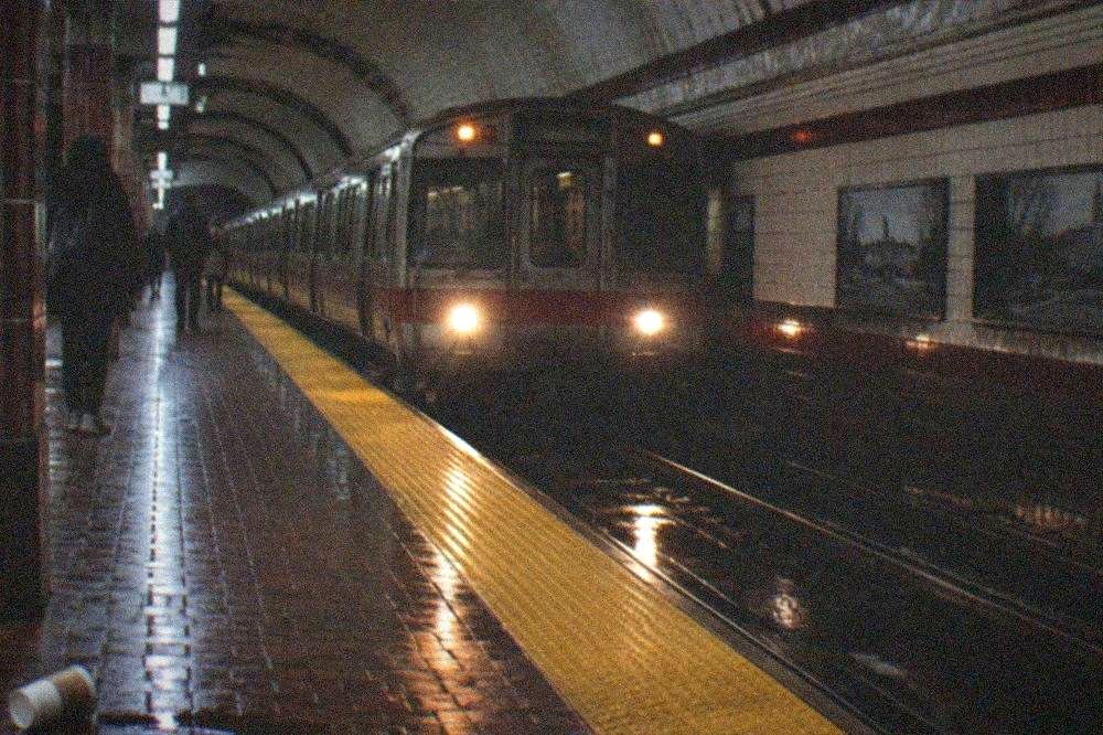 Red Line subway platform with a train arriving beneath a vaulted ceiling