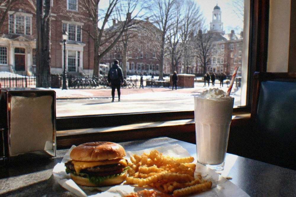 Simple restaurant table with a burger, fries, and a milkshake in daylight