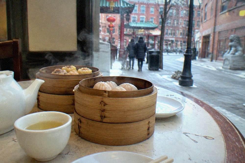 Steam rising from bamboo dim sum baskets on a restaurant table