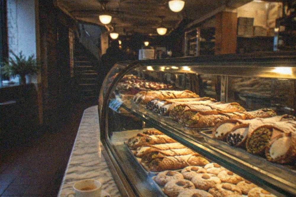 Pastry counter display of cannoli and Italian cookies at a North End bakery