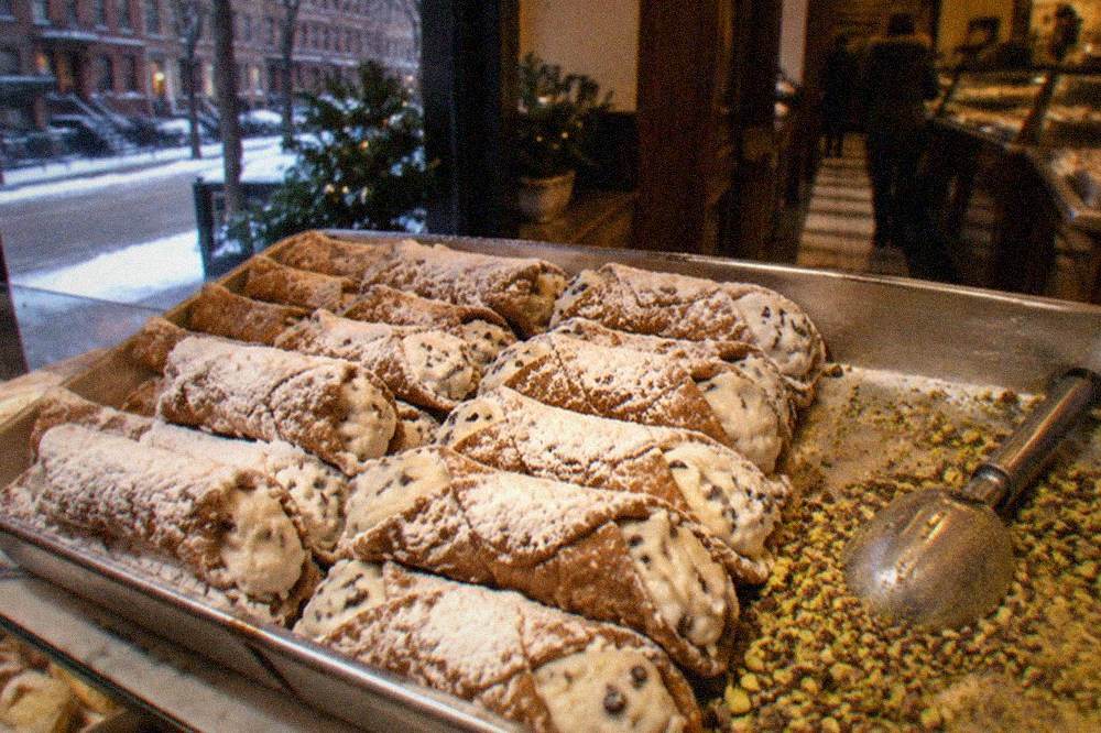A counter case filled with Italian pastries and cannoli at a North End bakery