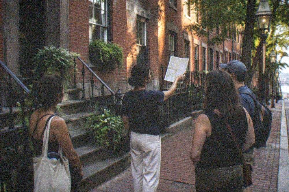 A tour guide leading a small group down a brick North End sidewalk