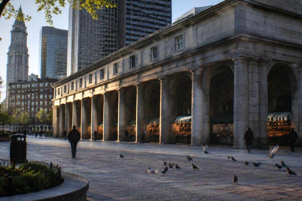 Historic granite market building with long colonnade and food stalls visible through the arches