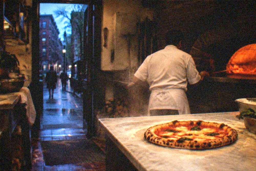 Wood-fired pizza with charred crust on a marble bakery counter